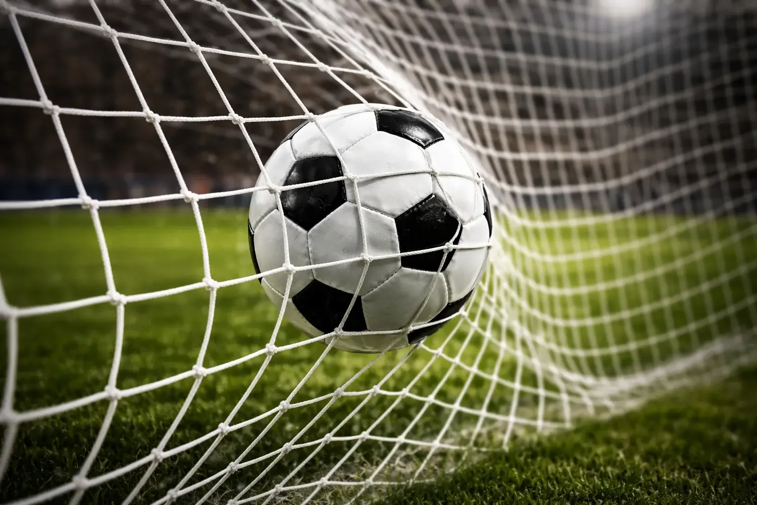 Pallone da calcio che entra in rete durante una partita sotto i riflettori dello stadio